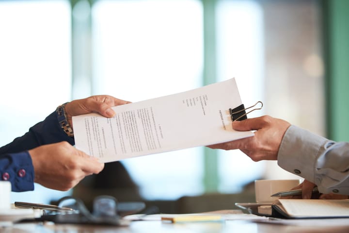 Folhas de contrato sendo entregues de uma pessoa para outra