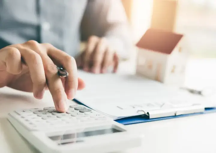 Homem calculando condições de refinanciamento de imóvel.