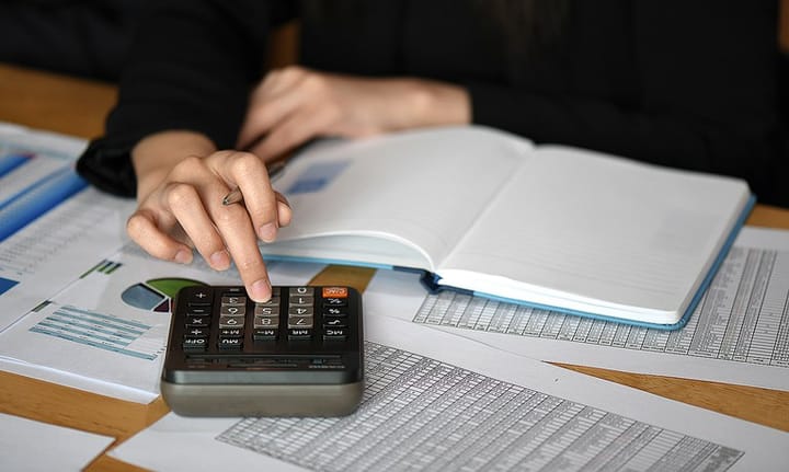 Pessoa calculando dados de planilha de gastos.